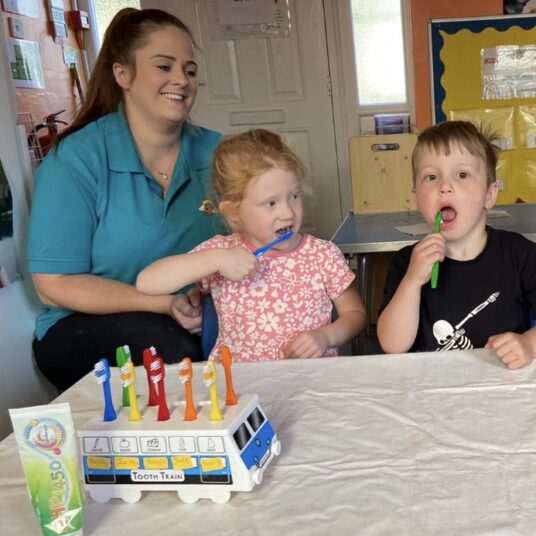 Nursery nurse helps toddlers brush their teeth
