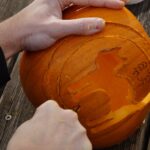 Photograph of person carving a Halloween pumpkin